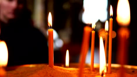 A-man-looks-at-a-lot-of-burning-candles-standing-in-the-sand