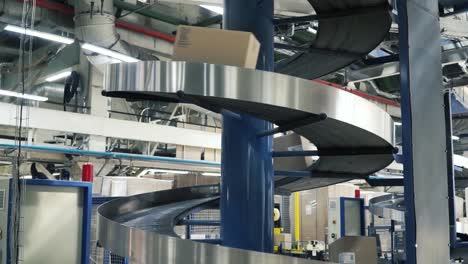 Cardboard-boxes-on-conveyor-belt-in-factory.-Clip.-Production-line-on-which-the-boxes-move-in-a-spiral