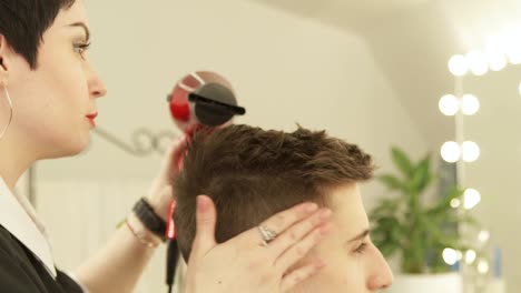 Hairdresser-drying-and-styling-male-hair-after-cutting-in-hairdressing-salon.-Close-up-barber-styling-hair-with-dryer-after-washing.-Finish-hairdressing-in-beauty-studio