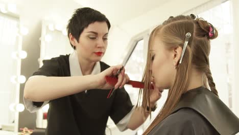 Woman-hairstylist-using-razor-for-cutting-long-hair-in-beauty-studio.-Close-up-female-hairstyle-in-hairdressing-salon