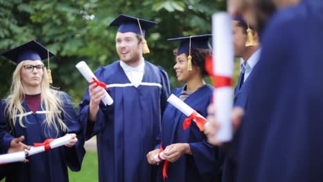 glückliche-Schüler-in-Mörtel-Boards-mit-Diplomen