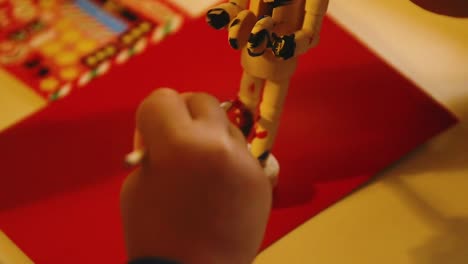 Video-Of-A-Young-Toddler-Boy-Making-A-Christmas-Wooden-Toy-Soldier-Craft-With-His-Mom-At-Their-Living-Room-Table