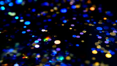 Defokussierten-schillernden-bunten-Glitter-Konfetti,-schwarzer-Hintergrund.-Urlaub-abstrakte-festliche-Bokeh-Lichtpunkte.