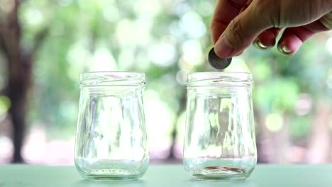 Sparen-Geld-in-das-Glas.-Hand-legen-Münzen-in-das-Glas-fallen.