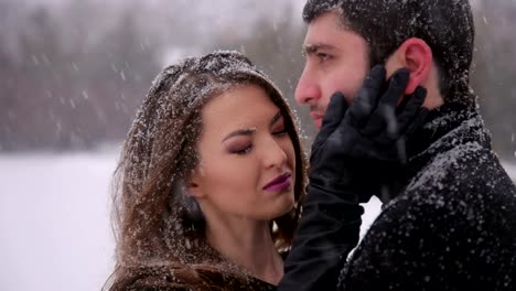 Couple-in-black-clothes-under-heavy-snow.-Wedding.