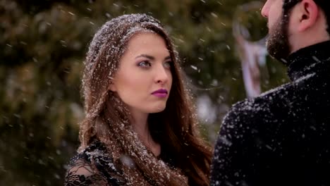 Couple-in-black-clothes-under-heavy-snow.-Wedding.