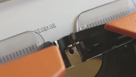 Close-up-footage-of-a-person-writing-DISEASE-on-an-old-typewriter,-with-sound