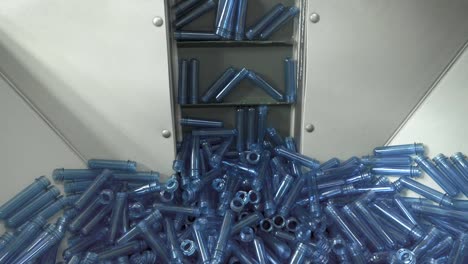 Big-pile-of-small-blue-blanks-lifting-up-on-the-factory-line-to-create-plastic-bottles.