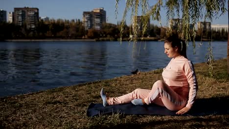 Hermosa-chica-en-un-chándal-en-el-paseo-marítimo-de-la-ciudad-hace-yoga.