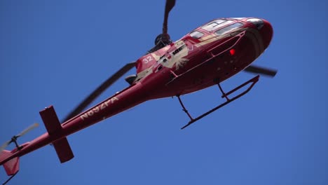 Slow-Motion,-die-roten-Hubschrauber-fliegt-über-Kopf-gegen-ein-strahlend-blauer-Himmel-hautnah