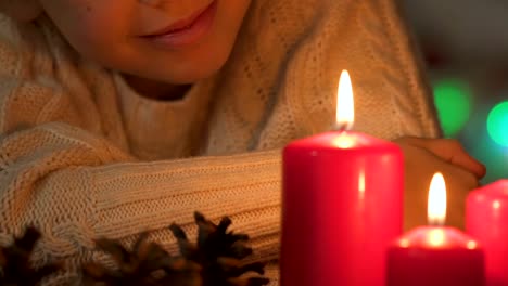 Niño-feliz-mirando-a-velas,-encendidas-esperando-milagro-en-Navidad-closeup