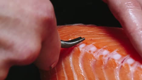 Chef-takes-out-bones-from-the-salmon-fillet,-cutting-fish-on-slices-for-cooking-sushi-in-4k-resolution-in-slow-motion