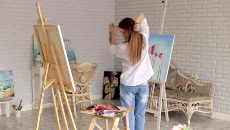 Un-artista-de-niña-feliz-girando-alrededor-de-ella-en-un-estudio-entre-muchas-pinturas.