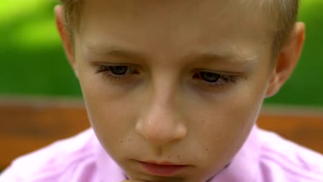 Unhappy-little-boy-with-cane-sitting-on-bench-in-park,-handicapped-sad-child