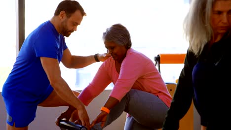 Entrenador-de-asistencia-a-senior-femenino-en-la-realización-de-yoga-4k