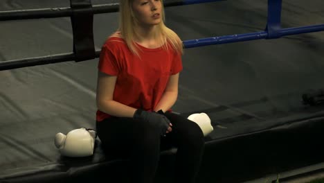 The-girl-the-boxer-sits-in-a-ring-and-looks-at-the-bandaged-hands