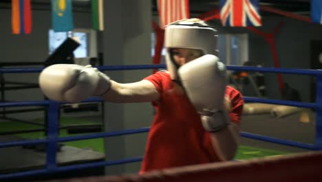 Young-girl-in-a-helmet-and-gloves-is-training-blows.-Closeup