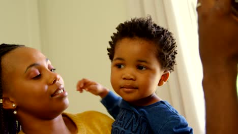 Frontansicht-der-jungen-schwarzen-Mutter,-die-ihr-Baby-in-einem-komfortablen-Haus-4k-hält