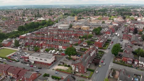 Aerial-footage-of-the-town-known-as-Crossgates-in-the-Leeds-area-of-West-Yorkshire-in-the-UK,-showing-a-typical-British-town-and-street-with-rows-of-houses-and-light-traffic-on-the-main-roads.