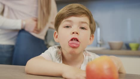 Niño-sentado-en-una-mesa-y-padres-bailando-detrás-de-él