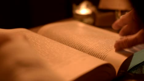 Big-Close-up-girl-magician-in-a-dark-room-with-candlelight-looking-for-a-spell-in-a-book.-Low-key-live-camera.