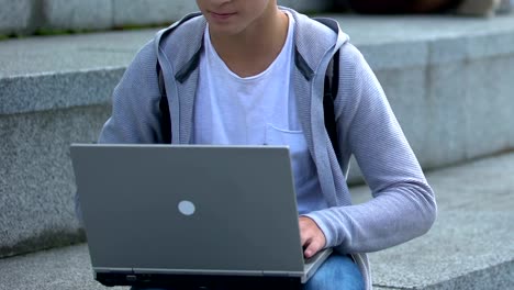Young-male-working-on-laptop-outdoors,-it-genius-or-smart-teenage-hacker,-app