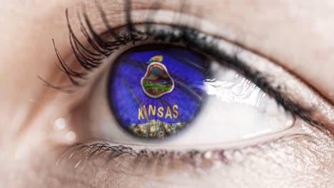 Woman-green-eye-in-close-up-with-the-flag-of-Kansas-state-in-iris,-united-states-of-america-with-wind-motion.-video-concept