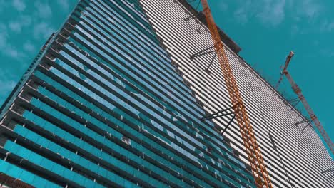 Kran-auf-einer-Baustelle-gegen-den-blauen-Himmel-baut-einen-neuen-Wolkenkratzer.-Gebäudebau