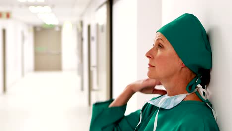 Tensed-female-surgeon-standing-in-corridor