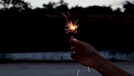 Descoloramiento-espumoso-en-una-mano-femenina-con-manicura-blanco-en-la-noche-en-la-playa,-primer-plano,-cámara-lenta