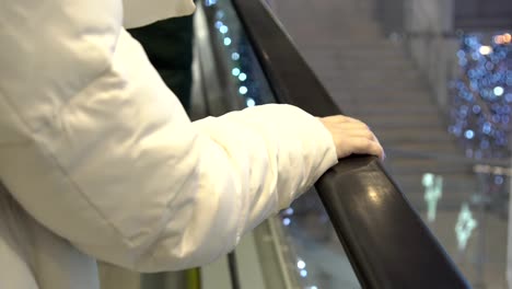 Point-of-view-of-a-woman-riding-an-escalator.-One-hand-visible