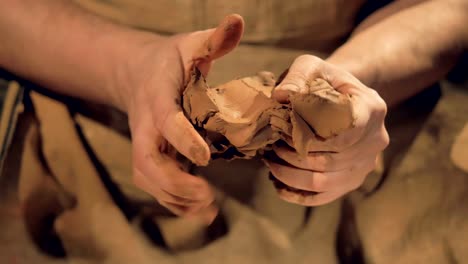 Potters-fingers-knead-a-medium-lump-of-brown-clay.