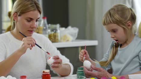 Niña-pintando-huevos-de-Pascua-con-mamá-y-la-abuela