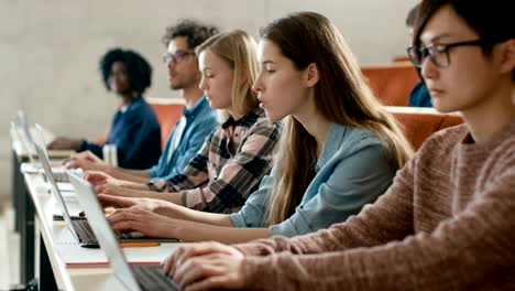 Zeile-der-Multi-ethnischen-Studenten-arbeiten-auf-den-Laptops-beim-hören-einen-Vortrag-im-modernen-Unterricht.-Helle-Jugendliche-Studie-an-der-Universität.