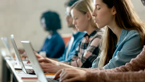 Zeile-der-Multi-ethnischen-Studenten-arbeiten-auf-den-Laptops-beim-hören-einen-Vortrag-im-modernen-Unterricht.-Helle-Jugendliche-Studie-an-der-Universität.