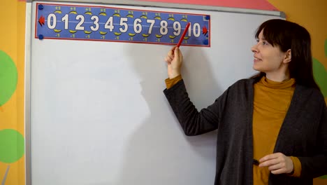 Female-teacher-stand-near-blackboard-in-elementary-school-teaching.