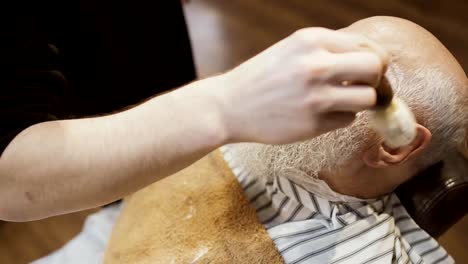 Barber-applies-shaving-cream-on-face-of-senior-man