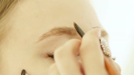 Close-up-process-painting-and-coloring-eyebrows-on-woman-face-in-makeup-studio.-Visagiste-using-cosmetics-brush-for-makeup-eyebrows-on-lesson-in-beauty-school