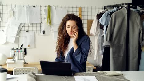 Empresario-exitoso-sastre-está-hablando-por-teléfono-móvil-y-usando-laptop.-Mujer-está-ocupada-ordenando-a-tela-proveedor-de-textil.-Concepto-de-puesta-en-servicio-de-diseño-de-ropa.