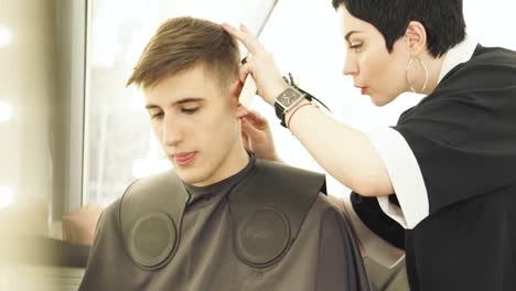 Haircutter-shaving-hair-during-male-hairdressing-in-barber-shop.-Hairdresser-doing-professional-hairstyle-with-shaver-in-beauty-studio