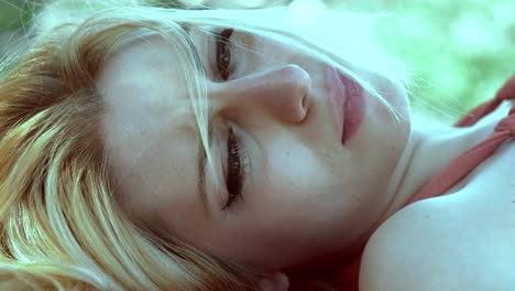 Tearful-sad-blonde-woman-lying-in-the-park.close-up