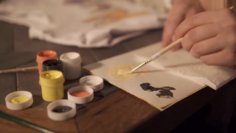 Artist-is-mixing-yellow-and-white-dyes-on-a-palette-before-drawing,-close-up