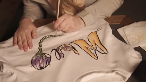 Woman-is-applying-pattern-on-a-white-sweatshirt,-close-up