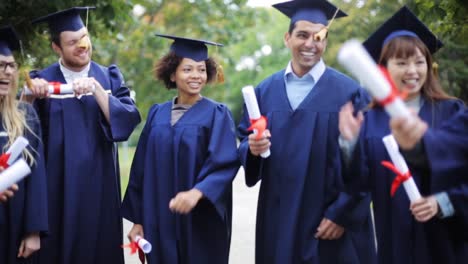 glückliche-Schüler-in-Mörtel-Boards-mit-Diplomen