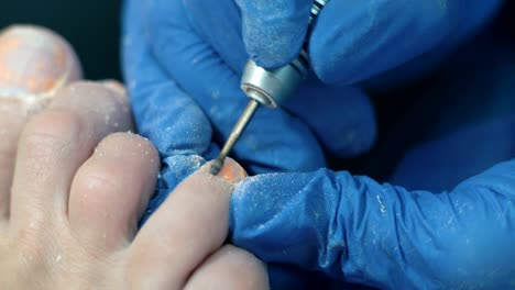 Extreme-close-up,-Maniküre-Master-in-blaue-Handschuhe-reinigt-alte-Lackschicht-mit-Nagel-Client