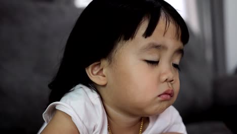 Baby-asian-girl-watching-TV-on-sofa-at-home.