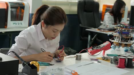 Woman-electronics-engineer-is-measuring-the-signal-in-the-electrical-circuit-in-her-workshop.-Girl-student-are-studying-electronics-in-classroom.