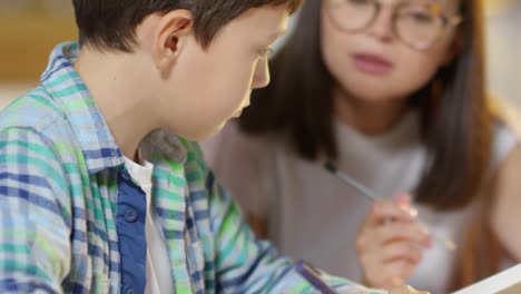 Kid-Doing-Homework-with-Help-of-Female-Tutor