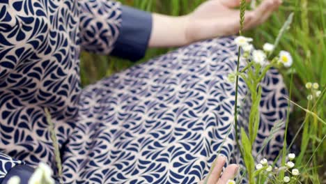 Woman-hands-resting-on-knees-in-lotus-pose,-young-female-meditates-outdoors-slow