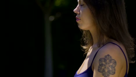 Close-up-yogi-woman-sits-in-lotus-position-relaxed-meditating-in-park-face-hands